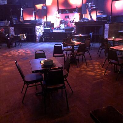 Club interior, tables lined up, stage area in the back