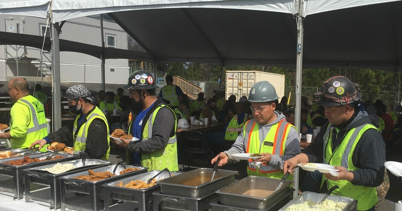 Outdoor buffet, construction workers helping themselves to food