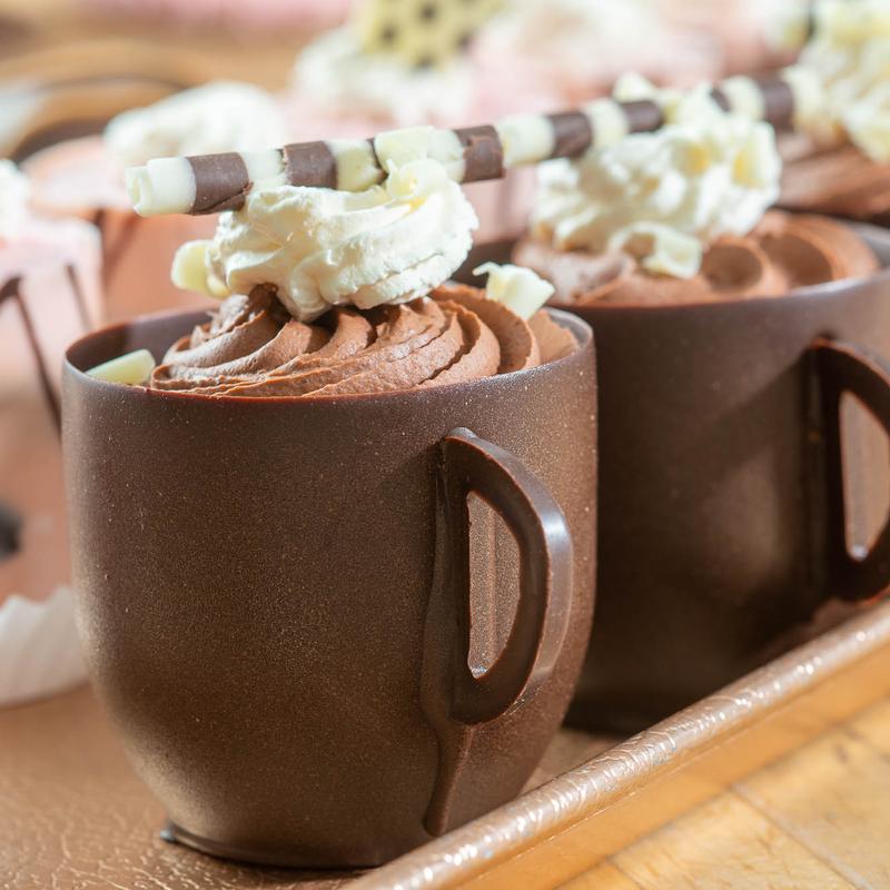 Edible chocolate mugs topped with whipped cream and waffle roll