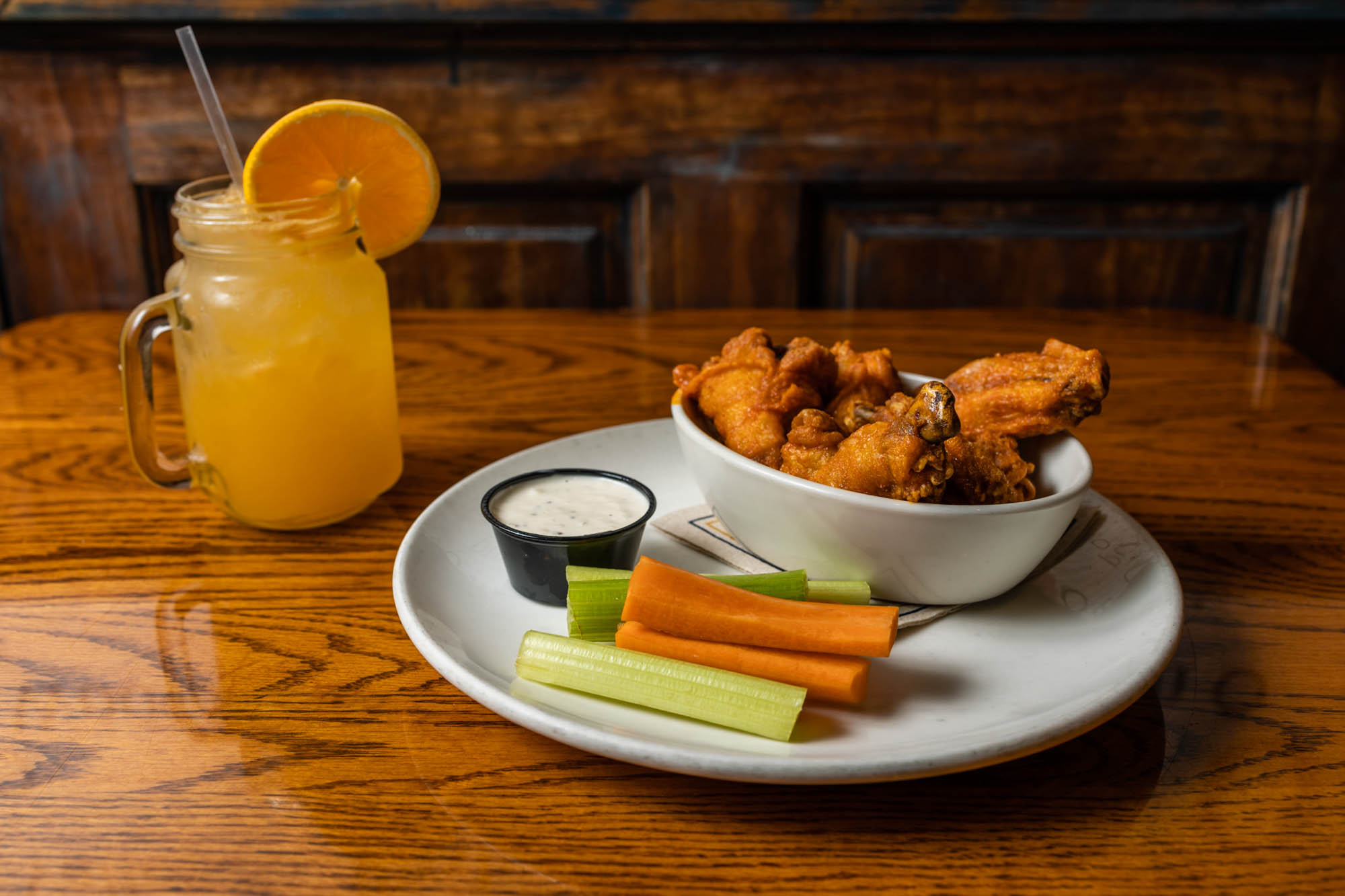 Beck’s Buffalo Wings with a sauce dip, celery and carrots on the plate, Orange Crush drink