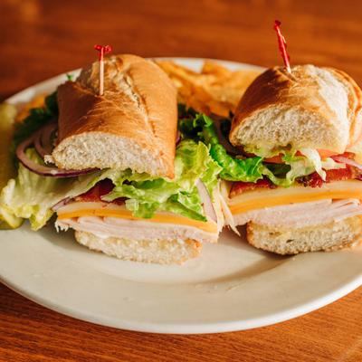 Turkey club sandwiches with lettuce, tomato, red onion, bacon and cheese