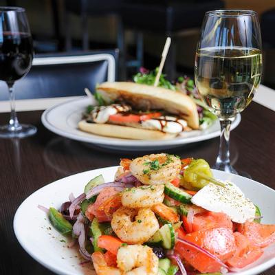 Grilled shrimp served with vegetables and cheese, a glass of white wine