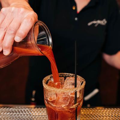 Bartender pouring Bloody Mary into a glass