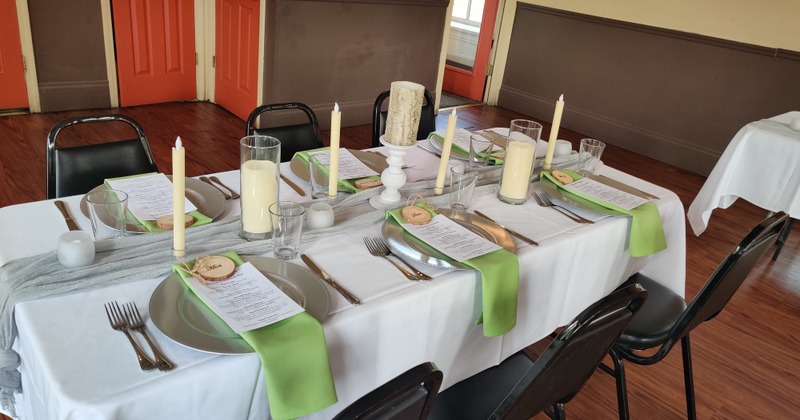 Interior, an arranged table with green napkins, tableware and candles ready for an event