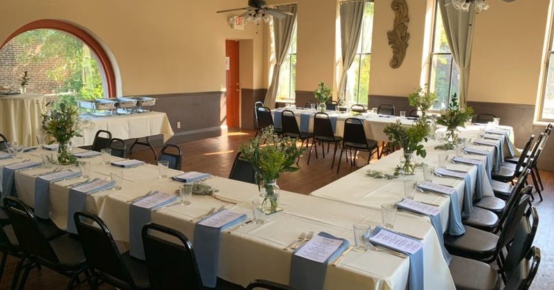 A room with long dining tables set for a formal gathering or event