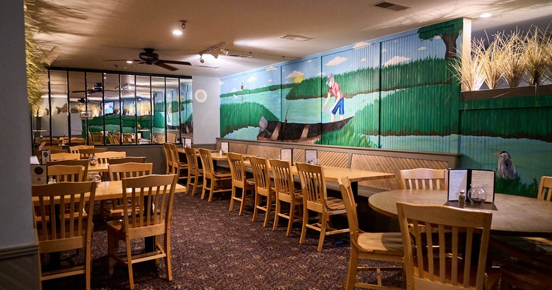 Interior, seating area, long banquette bench with tables, colorful fishing mural on the wall