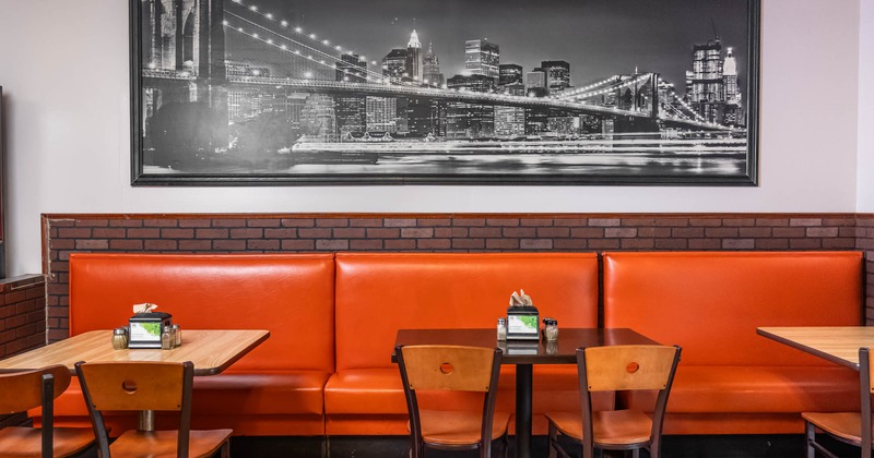 Interior, long banquette bench with wooden top tables and chairs, large Brooklyn bridge photo