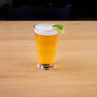 A refreshing beer with a slice of lime resting on a wooden table.