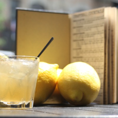 Translucent yellow cocktail with a straw and lemons