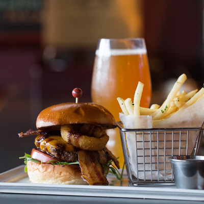 Bacon cheeseburger with onion rings and fries and a glass of beer