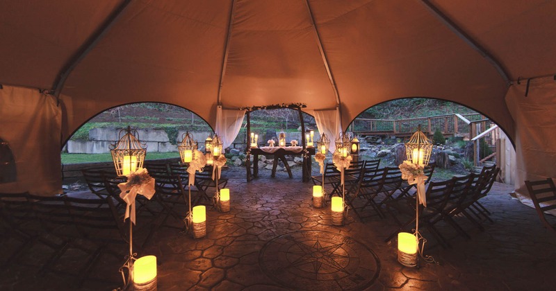 Exterior, outdoor ceremony tent with chairs and altar, warm candle lighting