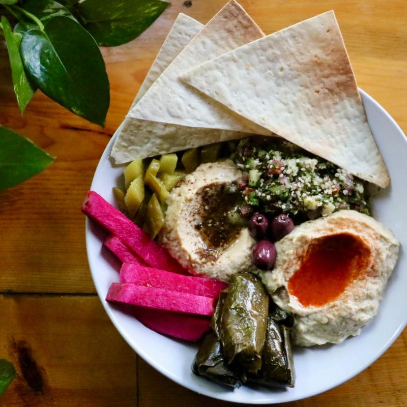 Mediterranean plate, with stuffed grape leaves, hummus, pickled vegetables, and pita chips.