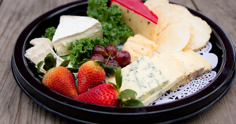 Assorted cheeses served with strawberries and grapes on a plate