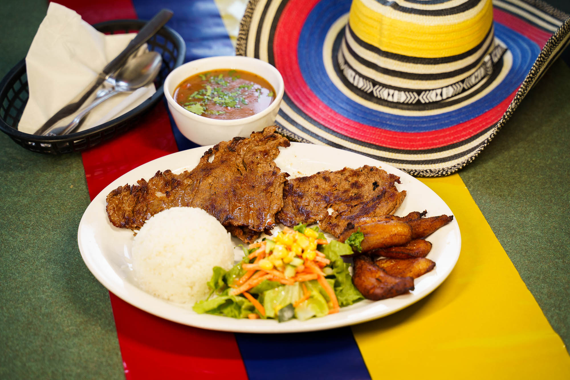 Grilled steak, served with white rice, beans, fried plantain, and salad