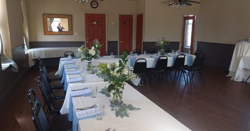 A long table with white linens flowers,  and blue tablecloths set up for an event or gathering