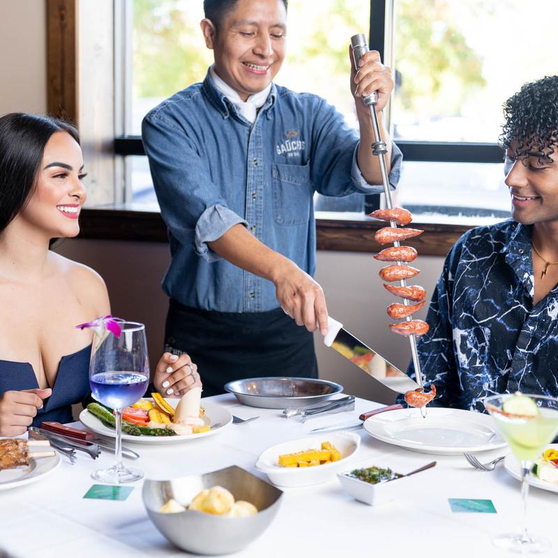 Employee serving food to a smiling couple at the table