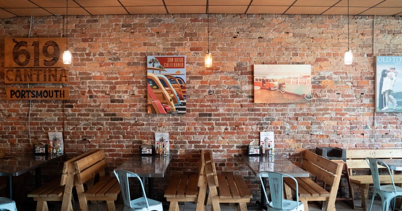 Interior, tables with benches and chairs, old red brick wall, restaurant logo on a wooden planks