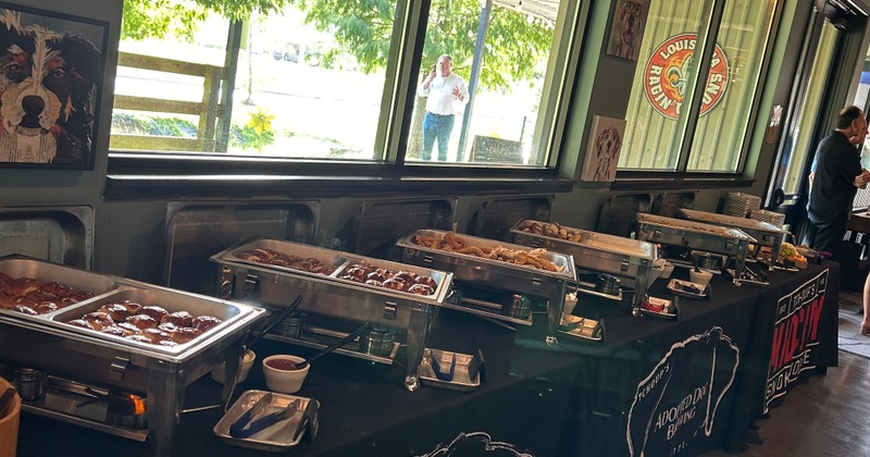 A buffet table at an event with several chafing dishes filled with food