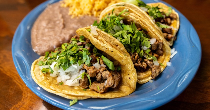 Steak tacos, with onions, cilantro, rice, and refried beans