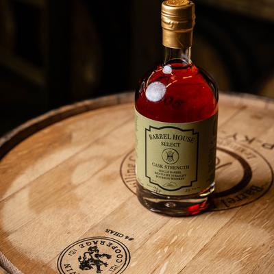 Cask Strength bourbon bottle on a barrel top.