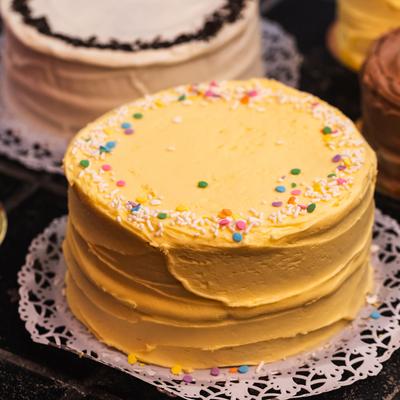 A yellow cake with buttercream frosting and sprinkles.