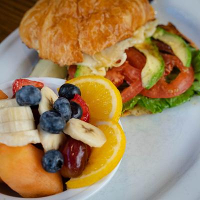 Chicken Avocado sandwich served with fresh fruit bowl.
