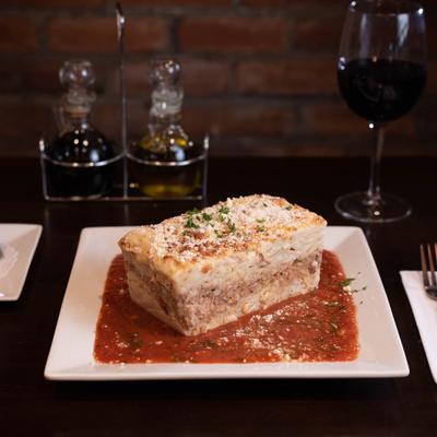 Lasagna, served with a glass of red wine.