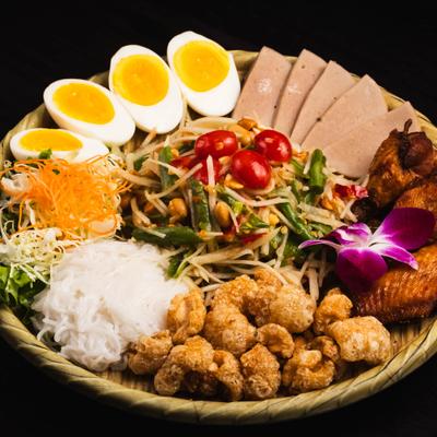 Bowl with various meats, boiled eggs, and veggies.