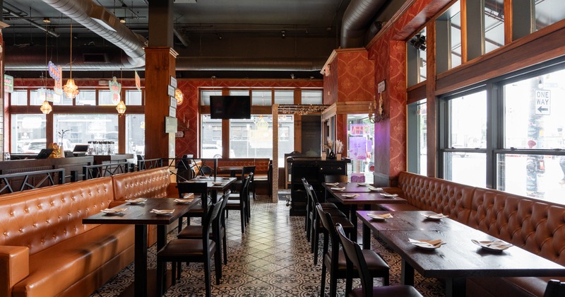 Interior, warmly decorated restaurant with leather booths, set dining tables, patterned tile floors