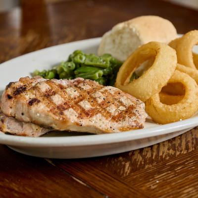 Grilled chicken served with onion rings, green beans and a bread roll.