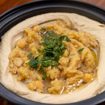 Hummus topped with chickpeas and fresh herbs, close-up.