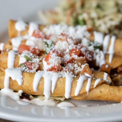 Flautas topped with cheese, sour cream, and salsa.