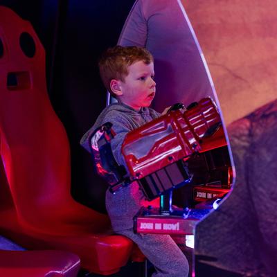 An excited kid playing a video game at the arcade area.