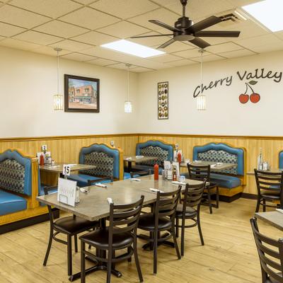 Cozy restaurant interior dining area with dining tables, chairs, and upholstered booths.