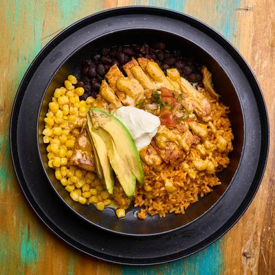 Rice bowl, with grilled chicken, beans, corn, cheese dip, pico, sour cream, and avocado.