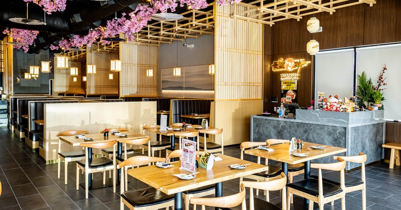 A Japanese restaurant - tables, booth seating, cherry-blossom ceiling decorations, paper lanterns.