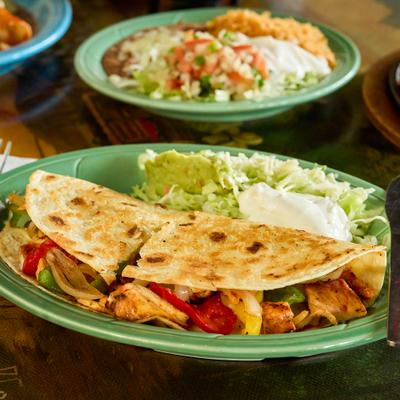 Chicken quesadilla served with shredded lettuce, guacamole, and sour cream.