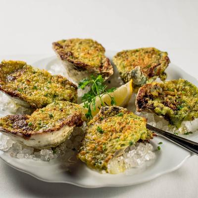 Herb-baked oysters on ice with lemon and parsley garnish.