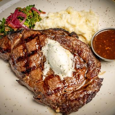 Grilled ribeye steak, with mashed potatoes, butter, and sauteed veggies.
