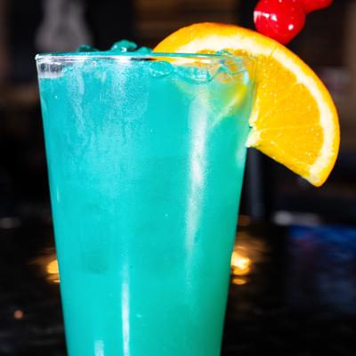 Blue cocktail with orange slice and cherry garnish.
