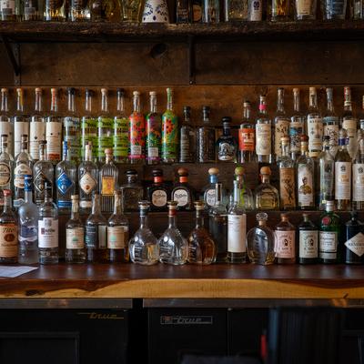 Assorted liquor bottles arranged on a bar shelf.