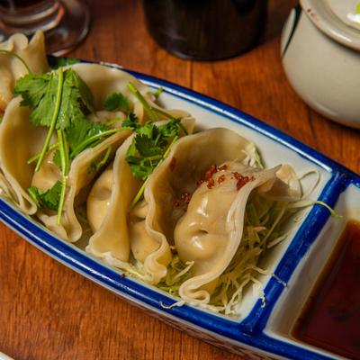Chicken Dumplings garnished with fresh cilantro and served with a dipping sauce.