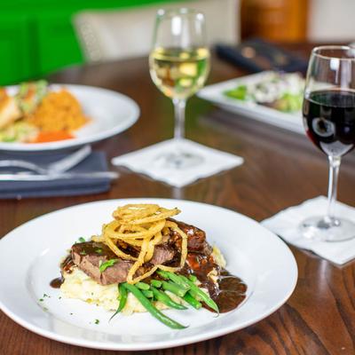 Short rib plate, other dishes and wine served on a table