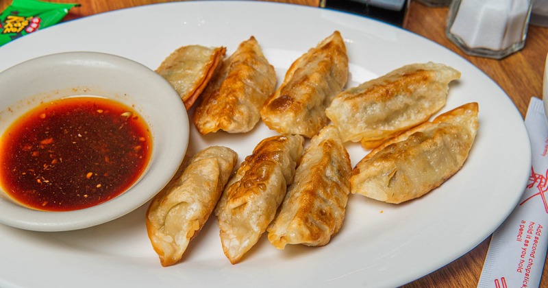 Pan-fried dumplings served with a dipping sauce