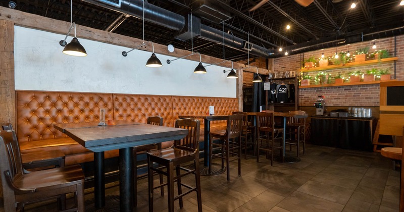 A modern restaurant interior with dark wooden furniture, leather booth seating, pendant lights
