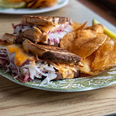 Reuben sandwich served with chips on a green-patterned plate.