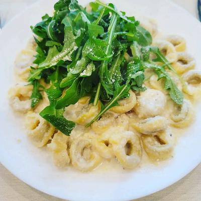 Tortellini in sauce, topped with arugula.
