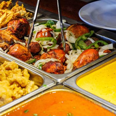 Indian food buffet trays filled with tandoori chicken, pakora, and curries.
