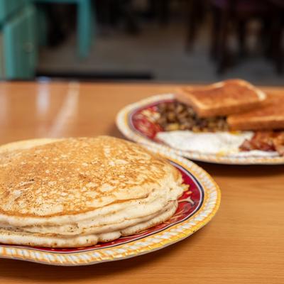 Plate of panecakes served on the table with one more breakfast dish.