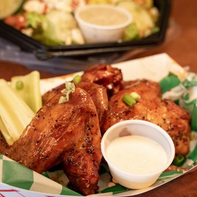 BBQ Wings served with a dipping sauce and celery sticks.